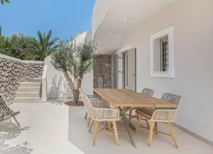 una mesa de madera y sillas en un patio en Pearl House - Luxurious new beach villa in Spetses stunning view, en Spetses