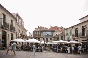 a group of people walking around a courtyard with tables and umbrellas at Hotel Restaurante Rúas in Pontevedra