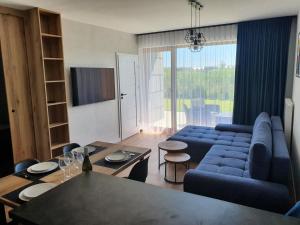 ein Wohnzimmer mit einem blauen Sofa und einem Tisch in der Unterkunft Smak wakacji in Sarbinowo