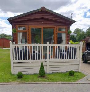 a small house with a white fence in a yard at Green Acres Retreat Lodge with Hot Tub in Malton