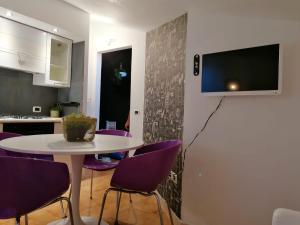 a table with purple chairs and a tv on a wall at Bramante-12 in Pescara