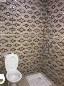 a bathroom with a toilet and a tiled wall at Hay salam réservé aux familles in Agadir