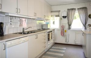 kuchnia z białymi szafkami, umywalką i oknem w obiekcie Pet Friendly Home In Asarum With Kitchen w mieście Asarum