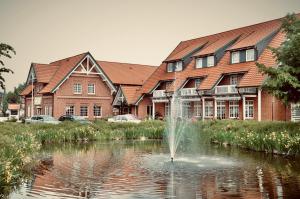 a fountain in the middle of a pond in front of a building at Schützenhof Ahlerstedt in Ahlerstedt