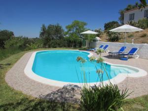 a pool with chairs and umbrellas next to a house at Cerca da Ponte in Almodôvar