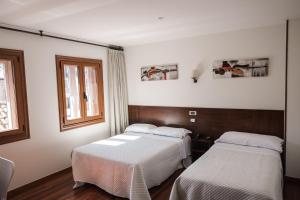 two beds in a room with a window at Hotel Restaurante Rúas in Pontevedra +73 photos
