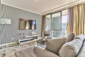 a living room with a couch and a tv at Harbour Bridge 1 Bedroom in Waterfront Precinct in Cape Town