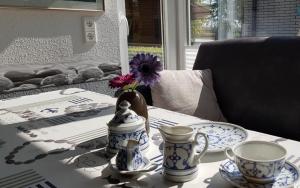 a table with two cups and a flower in a vase at Ferienhaus große Krabbe in Neuharlingersiel