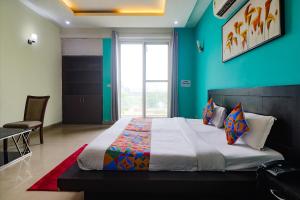 um quarto com uma cama grande e uma parede azul em FabExpress King's One em Noida