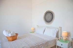 a white bedroom with a bed with two tables and two lamps at Larissa in Skala +27 photos