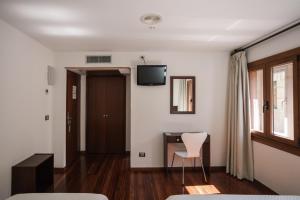 a room with a desk and a chair and a television at Hotel Restaurante Rúas in Pontevedra