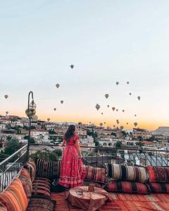 una mujer con un vestido rojo parada en un balcón con globos en Lord of Cappadocia Hotel en Göreme