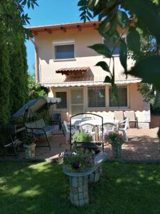 a house with chairs and an umbrella in the yard at Rose Vip Apartman in Hajdúszoboszló
