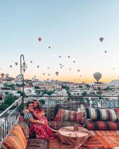 two people sitting on a couch on a balcony with hot air balloons at Lord of Cappadocia Hotel in Goreme