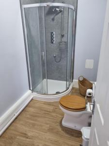 a bathroom with a shower and a toilet with a wooden seat at Tramway hotel in Pakefield +17 photos