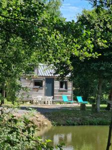 Ban-sur-Meurthe-Clefcy的住宿－Insolite Tiny House Sérénité Bien Être，船舱,两把蓝色椅子靠近水体