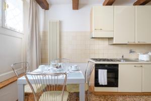 una cucina con tavolo, sedie e piano cottura di Frassinago Suites-BolognaRooms a Bologna