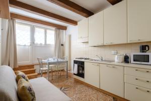 una cocina con armarios blancos y una mesa con sillas. en Frassinago Suites-BolognaRooms, en Bolonia