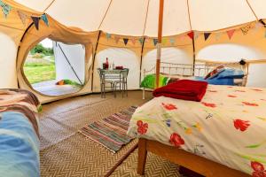 a tent with a bed and a table in it at Finest Retreats - Oak Lotus Belle Tent in Ilfracombe