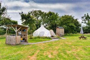 a white tent and a shed in a field at Finest Retreats - Oak Lotus Belle Tent in Ilfracombe