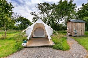 a tent with a wooden deck next to a shed at Finest Retreats - Oak Lotus Belle Tent in Ilfracombe