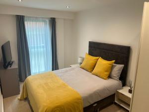 Un dormitorio con una cama con almohadas amarillas y una ventana en Lovely 2 Bed apartment in Leeds centre (Netflix), en Leeds