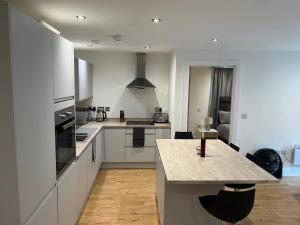 een keuken met witte kasten en een groot aanrecht bij Lovely 2 Bed apartment in Leeds centre (Netflix) in Leeds