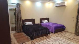 a bedroom with two beds with purple sheets and a window at City Square Gate 4 - Ultra Apartment - Full Sea View in Alexandria