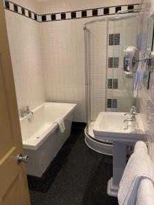 un bagno bianco con vasca e lavandino di Manor Hotel by Greene King Inns a Yeovil