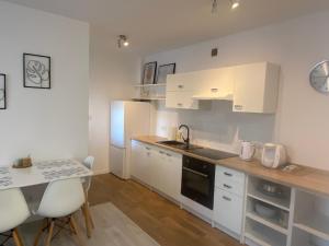 a kitchen with white cabinets and a table with chairs at Apartament Ełk Centrum II in Ełk