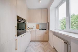 una cocina con armarios blancos y una ventana en Central Apartment in Architectural Street, en Kaunas