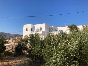 una casa bianca su una collina con cespugli davanti di IosAgnanti a Ios Chora