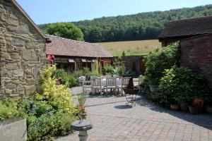 un patio con tavolo e sedie in un giardino di Garden Cottage at Eaton Manor a Eaton