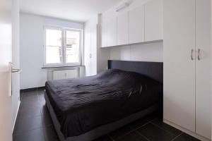 um quarto com uma cama preta num quarto branco em Appartement Ann em Blankenberge