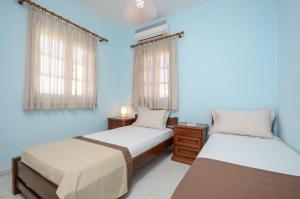 two beds in a room with blue walls and windows at Diamantis Kitesurf Villa in Mikri Vigla