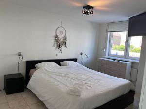 1 dormitorio con 1 cama blanca y reloj en la pared en Comfortabele woning mét omheinde tuin aan water voor 12 p, en Oostburg