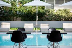 four tables and chairs with an umbrella next to a pool at Oktober Downtown Boutique Hotel in Rhodes Town