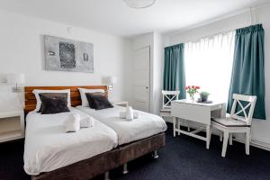 1 dormitorio con 2 camas, escritorio y ventana en familie Zwinkels, en Zandvoort