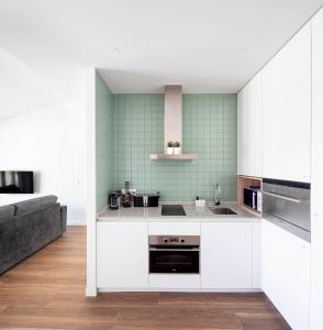 a kitchen with white cabinets and green tiles at Invino Apartments in Logroño
