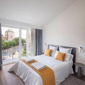 a white bedroom with a large bed and a large window at Invino Apartments in Logroño