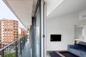 Invino Apartments في لوغرونيو: غرفة مع شرفة مع أريكة وتلفزيون