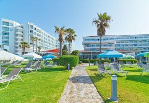 a group of lounge chairs and umbrellas in a park at Leonardo Cypria Bay in Paphos