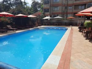a large blue swimming pool with tables and umbrellas at Brickwood Apartments in Nairobi