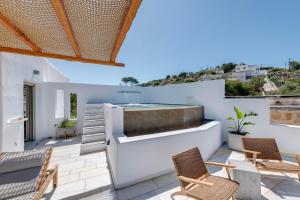 eine Terrasse mit Stühlen und einem Whirlpool an einer weißen Wand in der Unterkunft Calma Boutique Hotel in Posidhonía