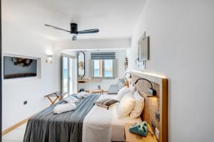 1 dormitorio con 1 cama grande y paredes blancas en Calma Boutique Hotel en Posidhonía