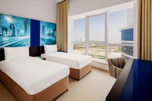 a hotel room with two beds and a window at Adagio Premium Dubai Al Barsha in Dubai