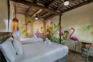 una camera con due letti con fenicotteri dipinti sulle pareti di Hidden Treehouse Tulum Eco-Hotel a Tulum
