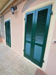 a pair of green doors on a pink building at Casa marciana alta in Marciana +6 photos