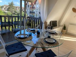 een glazen tafel en stoelen in een kamer met een balkon bij Escapade marine à 'l'Abri Côtier' in Deauville
