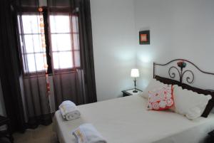 ein Schlafzimmer mit einem weißen Bett mit Kissen und einem Fenster in der Unterkunft Apartamentos Gharb Diem in Tavira